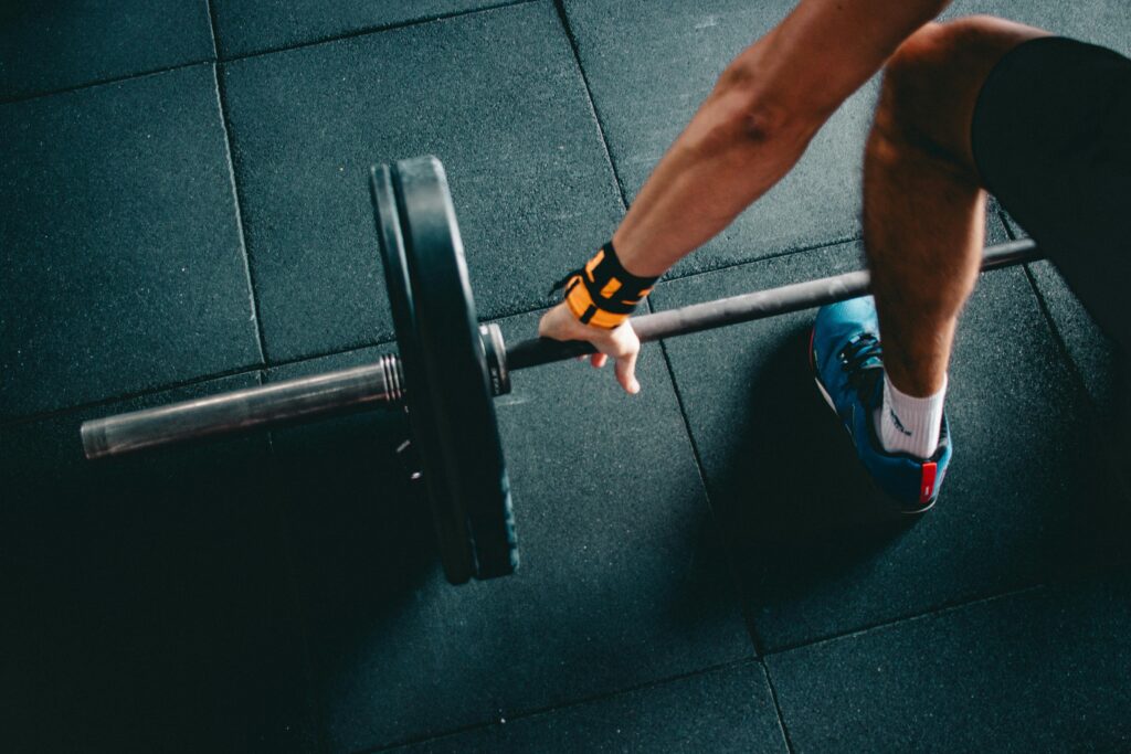 Close-up of a person lifting a barbell in an indoor gym, focusing on strength training.